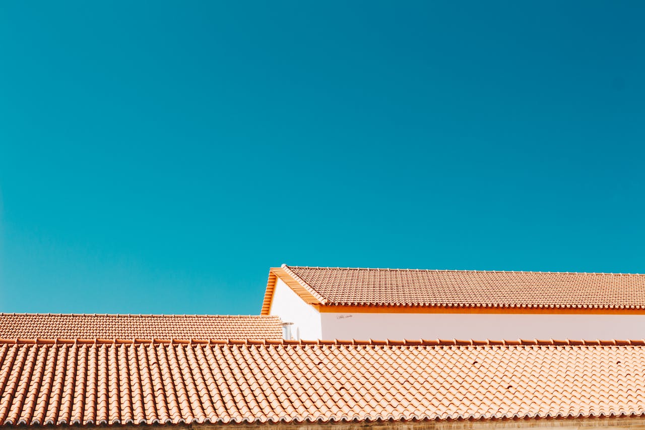 A serene image of terracotta roofs contrasting with a vibrant blue sky, showcasing architectural simplicity.